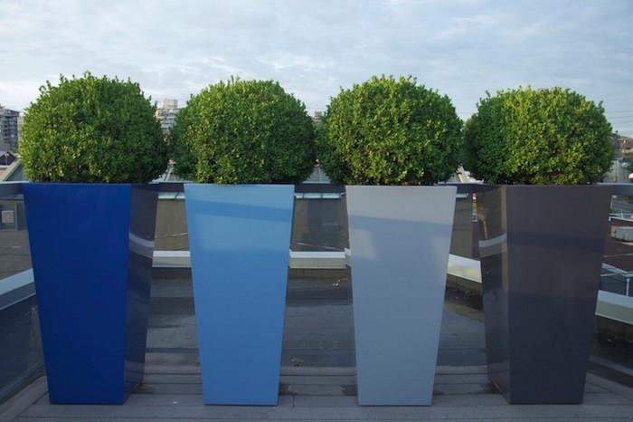 visoki kvadratni lončki za oblikovanje s krogličnimi rastlinami, ki skrivajo pogled na teraso