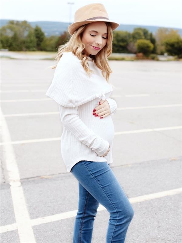 motinystės drabužiai, atsitiktinė nėščia moteris atrodo baltoje palaidinėje ir šviesiuose džinsuose su bohemiška smėlio spalva