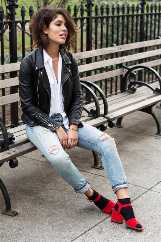 rock chic videz s pari lahkimi raztrganimi kavbojkami v kombinaciji s črno usnjeno jakno s čepki, model rdečih sandalov s črnimi nogavicami