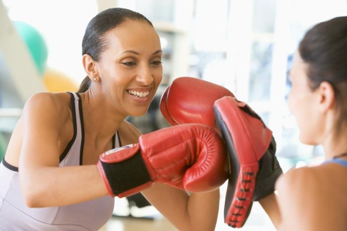 športni trening, ženski boks, rdeče boksarske rokavice, pudrasto roza športna obleka, boksarska telovadnica