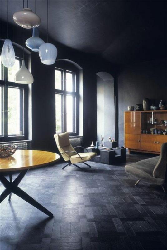 graži svetainė su juodu muilu grindimis-parketas ir apvalus stalas su šviesiomis medinėmis juodomis lubomis