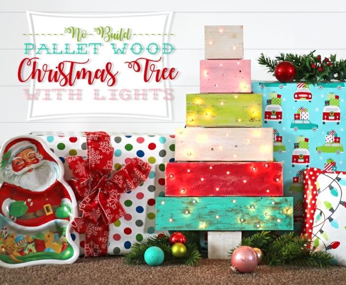 popierinis Kalėdų Senelis, didelė dovanų pakuotė, kalėdiniai rutuliai, mažos kalėdinės lemputės, dažytos padėklų lentos ir pakabinamos lempos
