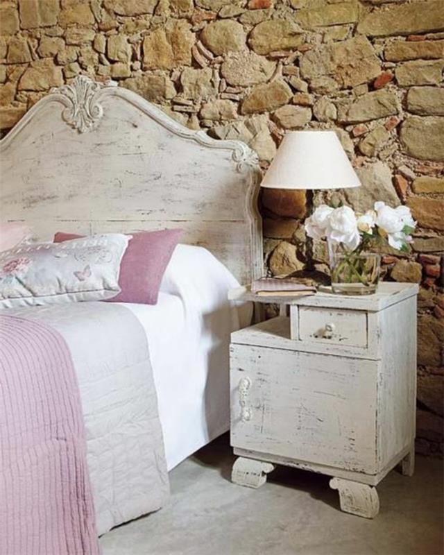 gražus miegamasis su akmens efekto siena ir baltos gėlės ant papildomų baldų