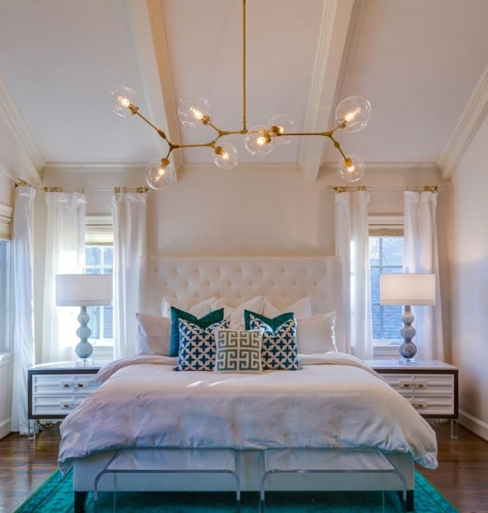 romantiškas miegamasis, molekulių lempa, balta galvūgalis, mėlynos ir baltos pagalvėlės, naktiniai staleliai su laikymo vieta