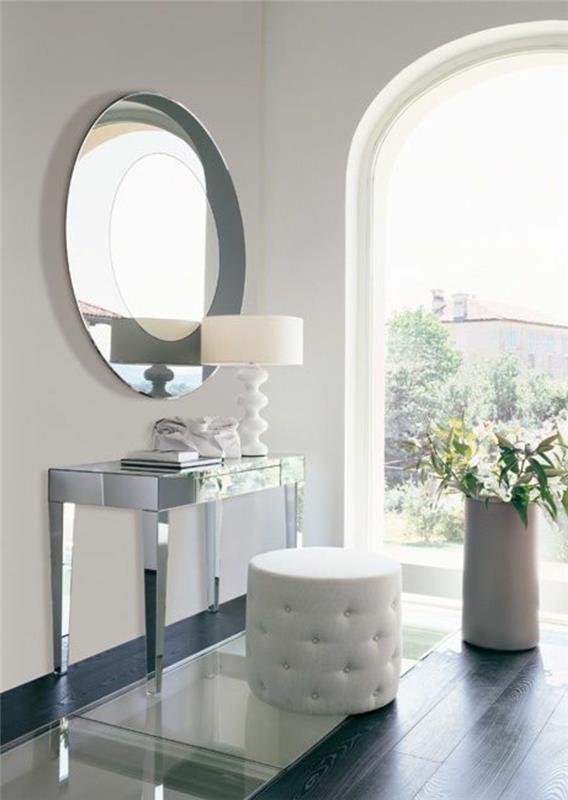 gražus tualetinis staliukas su apvaliu veidrodžiu ir balta odinė taburetė balta lempa šalia veidrodžio