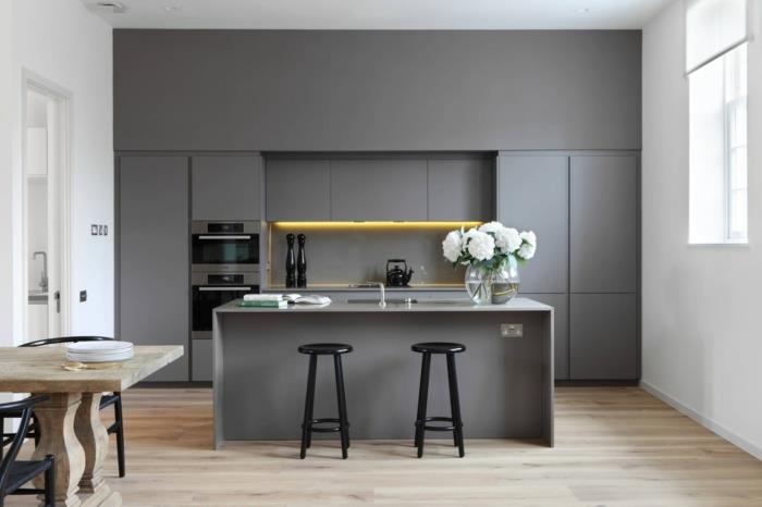 šiuolaikiška pilka virtuvė, neapdorotas medinis stalas, virtuvės dažų spalva, juoda sala ir išmatos