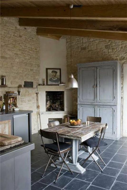 gražiai kaimiško stiliaus virtuvė ir pilkos plytelės-medinis stalas ir didelė plieninė liustra