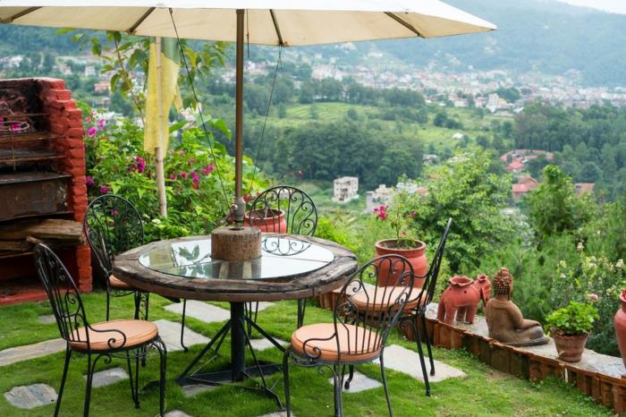 Apvalus juodai dažytas geležinis stalas ir kėdės, vaizdas į kalną, sodo terasos apdaila, nedidelis vėsus terasos išdėstymas