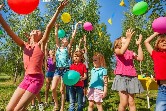 çimenlerin üzerinde renkli doğum günü balonlarıyla oynamak, çeşitli yaşlardaki çocuklarla çocuk doğum günü partisi
