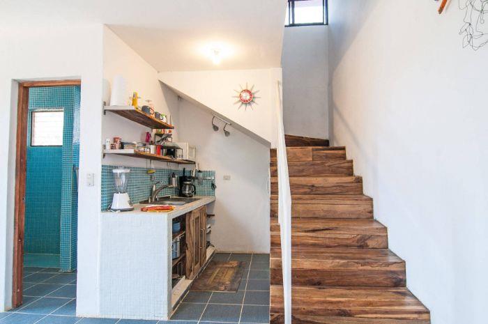 bela kuhinjska niša pod stopnicami z lesenimi vrati odprtimi lesenimi policami modra ploščica splashback