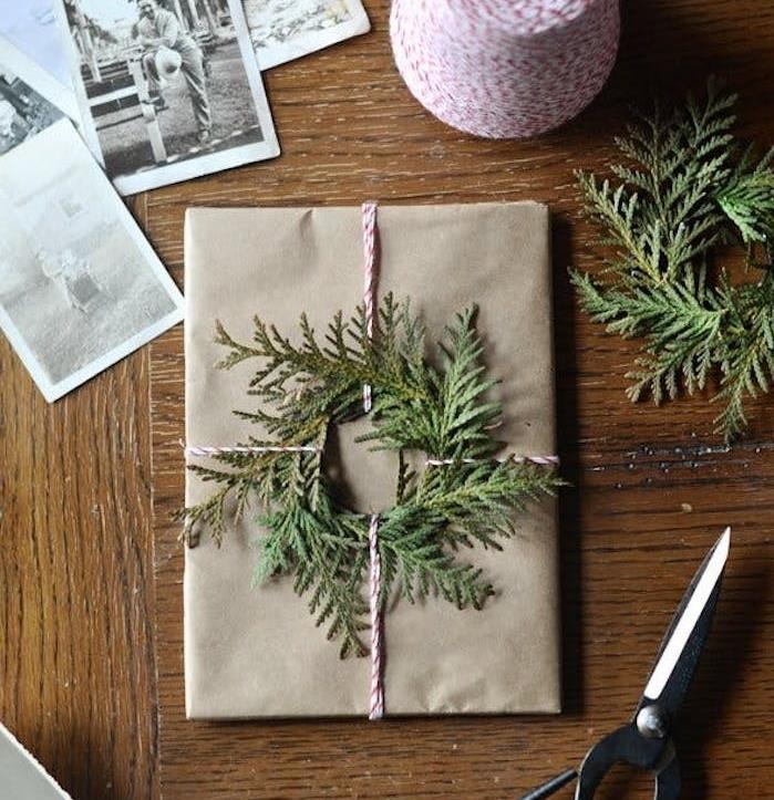 božično darilo iz kraft papirja z okrasom iz vencev iz zelenih vej in rdeče -belimi vrvicami