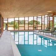 Sala de piscina con dos grandes paredes de vidrio.