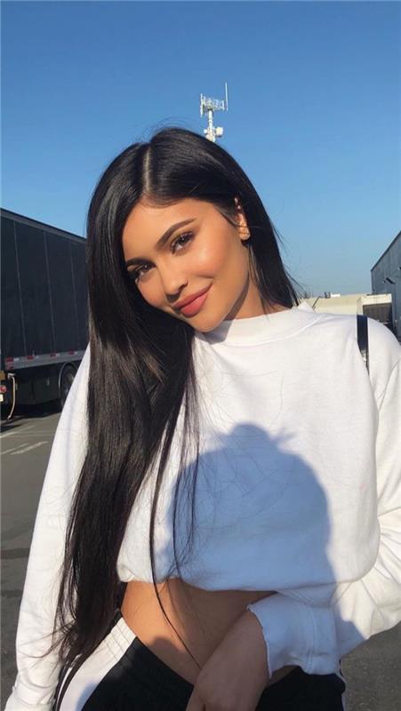 Kylie Jenner gatvės stiliaus baltos viršutinės juodos ir baltos kelnės ir ilgi juodi plaukai