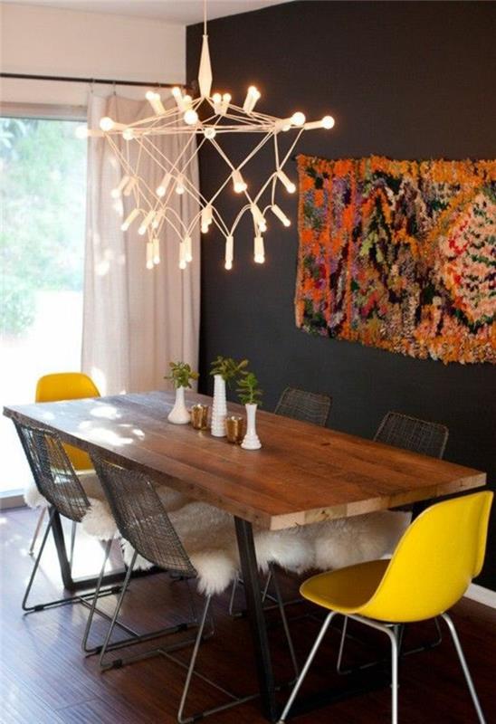 Sala da pranzo con una parete nera e un lampadario di design, arredamento con tavolo di legno e sedie gialle