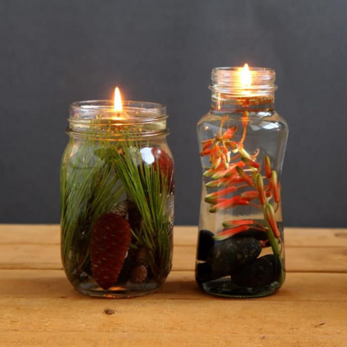 stiklainė lempa su augaliniu aliejumi ir plaukiojančia dagtimi, papuošta augalais ir akmenukais