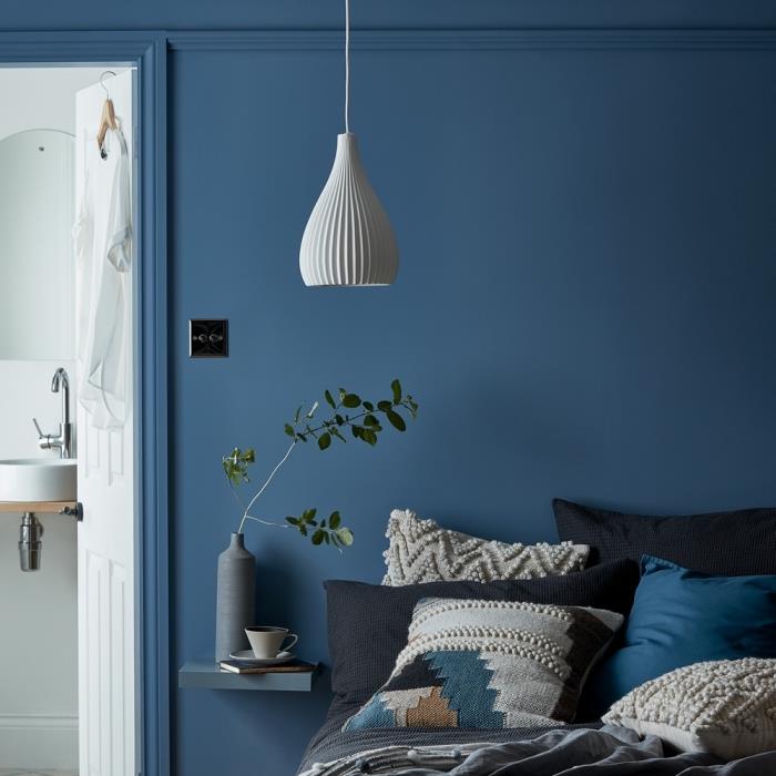 mavi tonlarında minderlerle kaplı bir koza ile koyu mavi duvarlar ile ana yatak odası dekor fikri