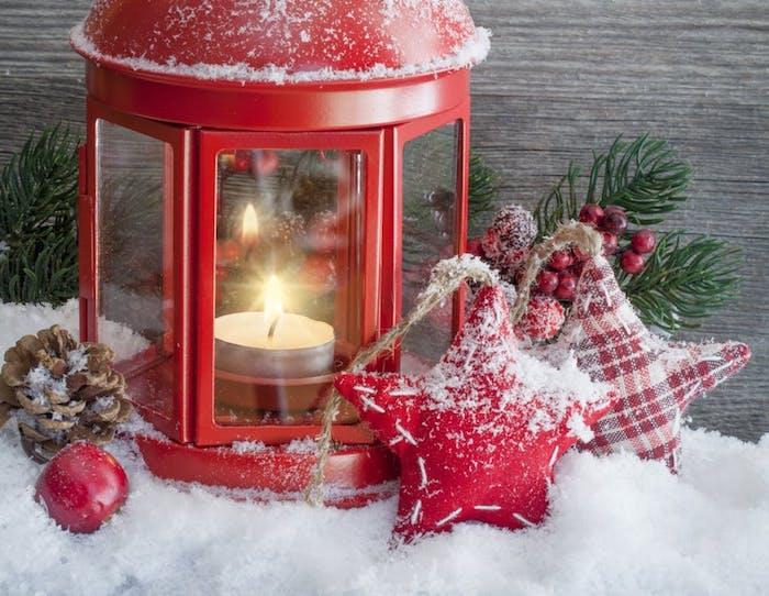 kalėdiniai tapetai raudoname žibinte su žvake, kankorėžiu, mažomis žvaigždžių formos pagalvėlėmis, pušies šakomis