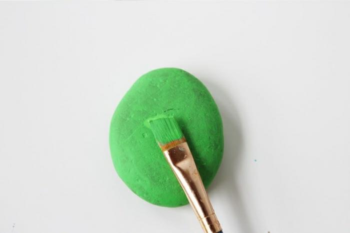 Idee lavoro arttigianale con un sasso dipinto di colore verde con un pennello