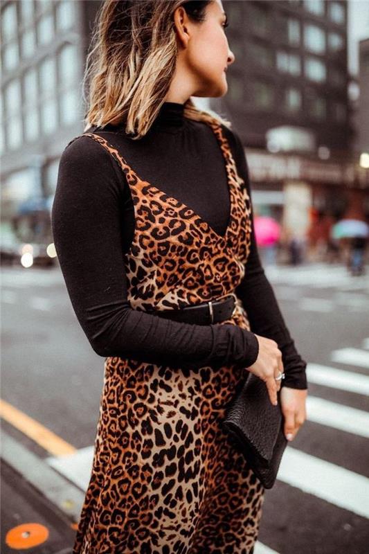 ženska, ki stoji sredi ulice, padajo modni trendi, nosi črno polo bluzo, obleko z leopardovim tiskom na vrhu
