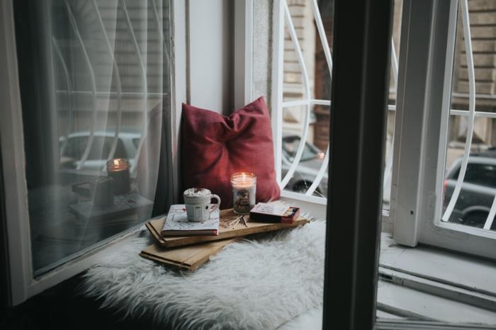 Kokonavimo vietos kampas su žvake ir knyga, išgerkite karšto šokolado šalia kokono nuotraukų lango