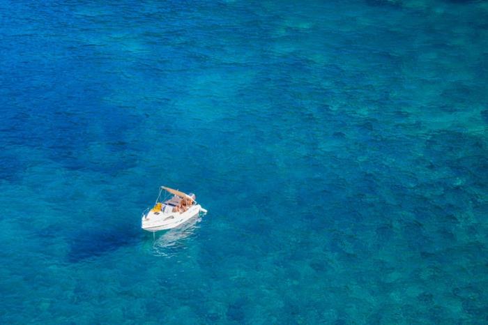 didelė mėlyna, balta turistinė valtis skaidriai mėlyname vandenyje, vandenyno viduryje, rojaus salos, rojaus kraštovaizdis