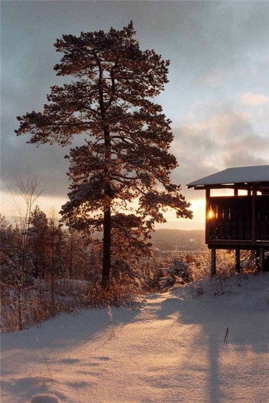 Noel duvar kağıdı fikri, dağların üzerinde gün batımı ve ahşap bir ev ile kış temalı fotoğraf