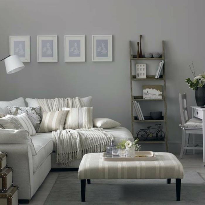 pilka pufas, balta kampinė sofa, senovinė knygų lentyna, pilkos miegamojo sienos, smėlio spalvos spausdintos pagalvės