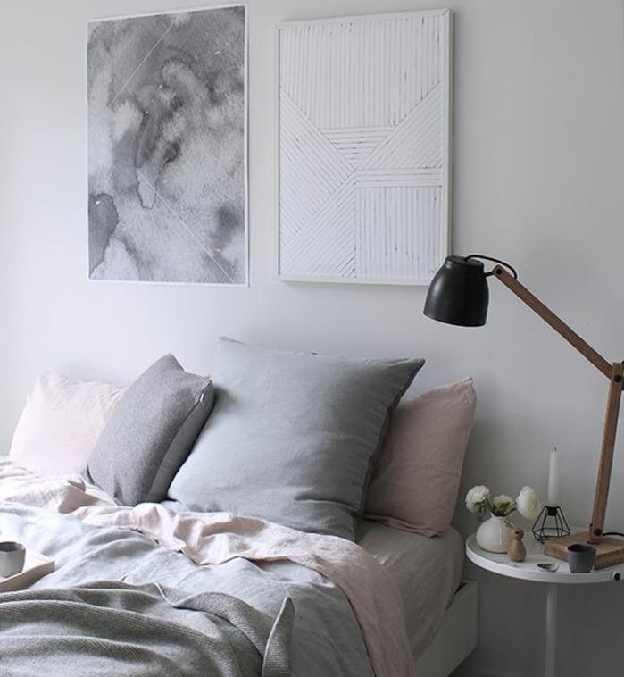 rožnato in sivo posteljnina, siva miza, roza in sive blazine, nočna svetilka v industrijskem slogu, bela barva sten, preprosta dekoracija spalnice
