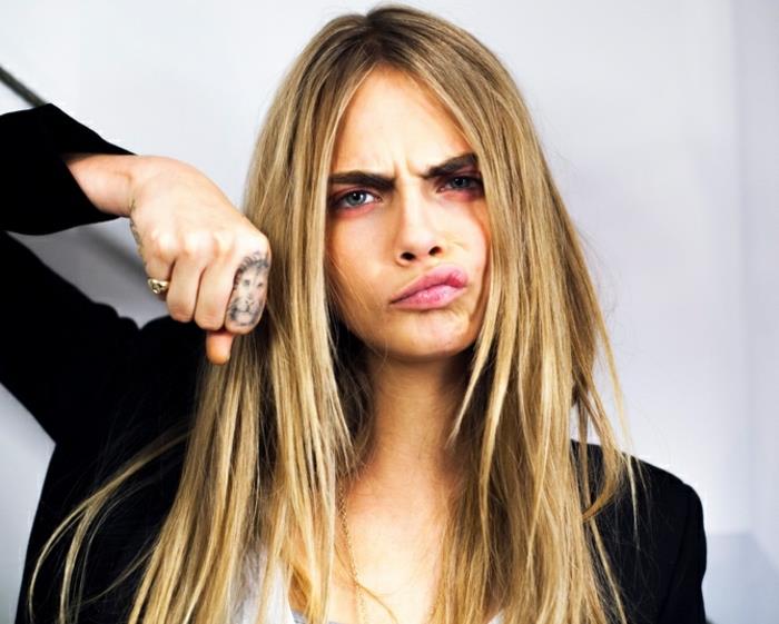 cara delevingne z dolgimi svetlimi lasmi, tetovaža leva, na prstu, tetovaže prstov za ženske, črni jopič