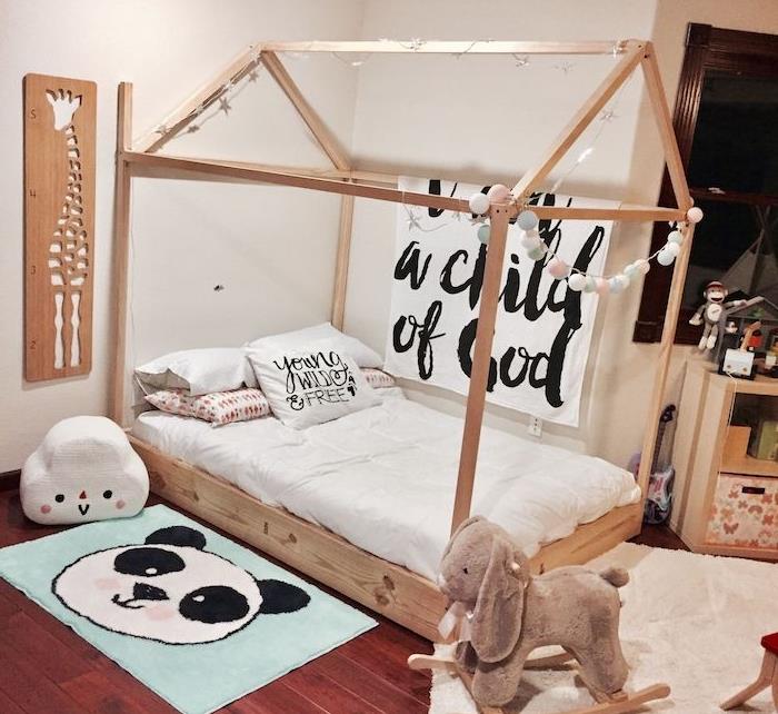 baltos sienos, žaidimų namų stiliaus medinė lova, tamsaus medžio parketas, baltos sienos, supamas arklys, mielas vaikiškas panda kilimėlis
