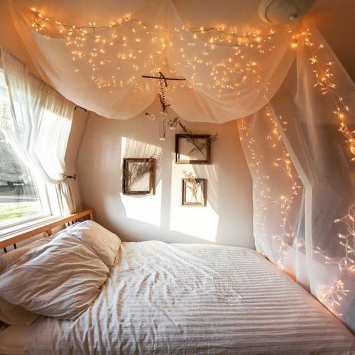 lova su baldakimu, svetingas miegamojo vaizdas, balti sienų dažai, kelios lempos virš baltų užuolaidų