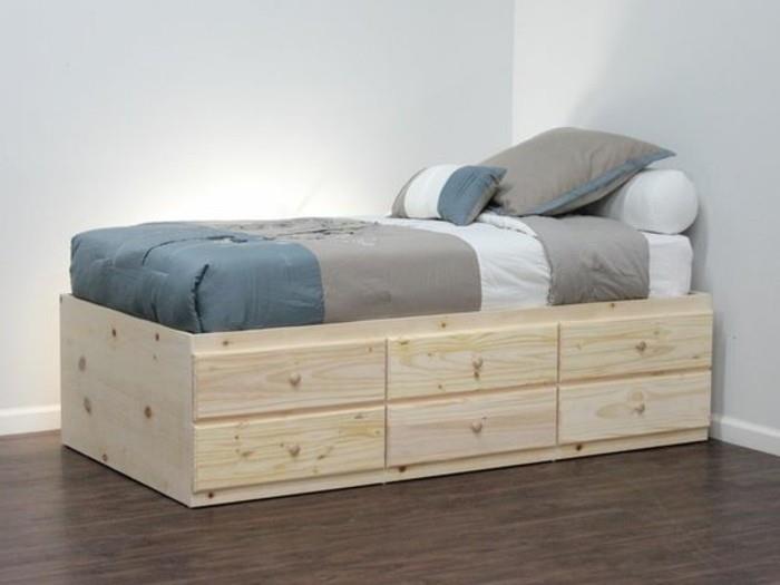 varna postelja-v-svetlem-lesu-temno-parket-tla-stena-svetlo-modro-posteljnina-sivo-modra