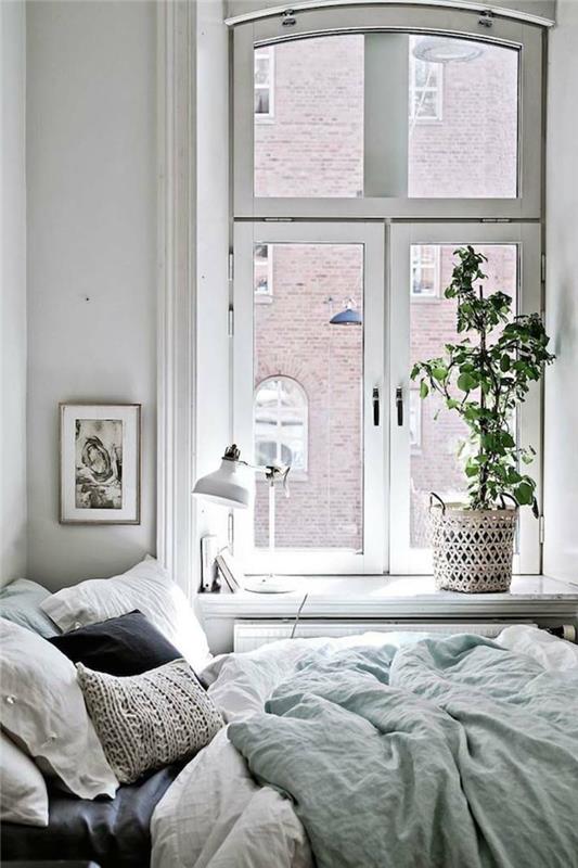 jauki lova ryškiai baltame miegamajame, kaimiškas sodinukas, pilkų ir baltų dažų rėmas, žalias augalas, balta stalinė lempa