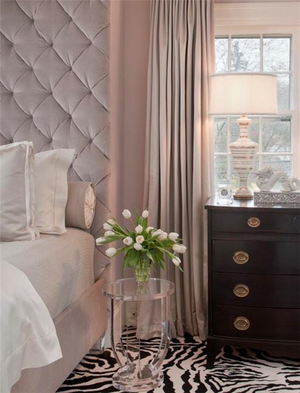 roza postelja z oblazinjenim vzglavjem in belim posteljnino, starinski leseni predalnik, preproga iz zebre, roza zavese, roza barva za spalnico za odrasle