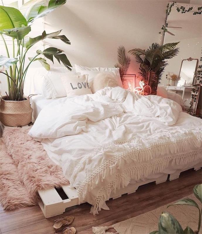 lovos pagrindas balintame padėkle su čiužiniu viršuje ir baltu linu, kambariniai žali augalai, džiunglių dekoro dvasia, rožinis avikailių kilimas, miegamasis „tumblr deco“