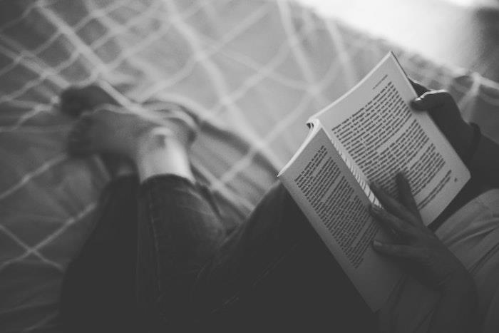 Črno -bela fotoknjiga, simbolična črno -belih barv, ženska v postelji s knjigo v rokah