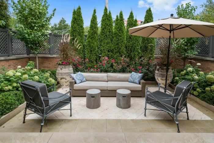 Beyaz kanepe ve gri koltuklar, açık veranda şemsiyesi, mobilyalı bir bahçe terası kurun