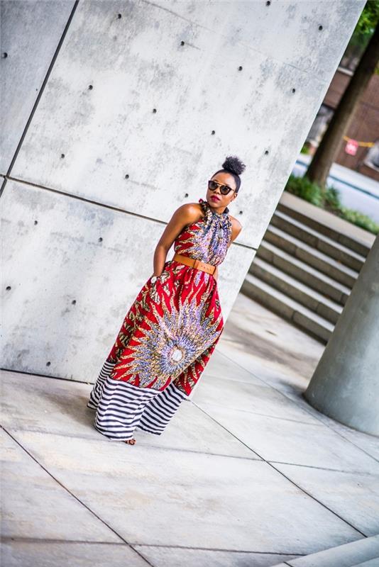Afrikos apranga šiuolaikinei moteriai, ilga ir krentanti suknelė su Afrikos rašto didele saule, su juostelėmis apačioje, dėvėta diržu ties juosmeniu