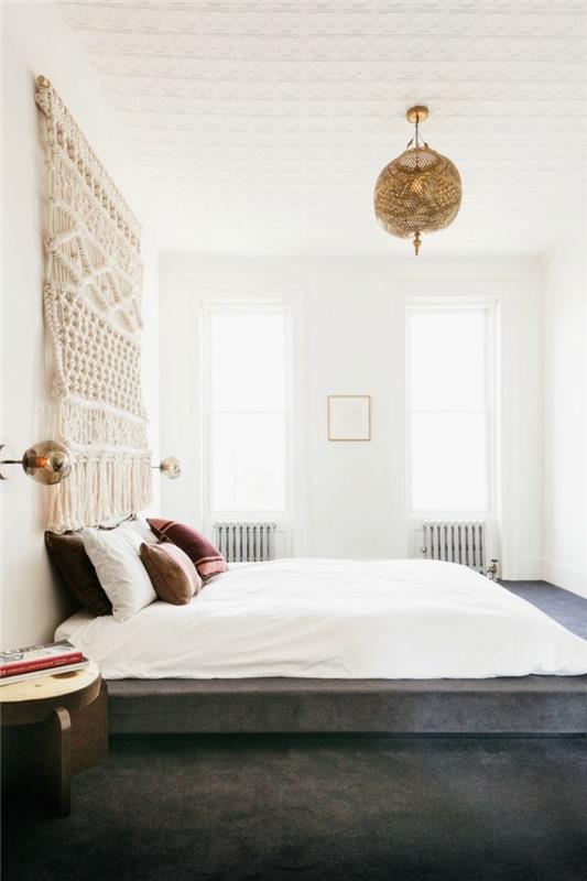 bohemiško stiliaus suaugusiųjų miegamojo pavyzdys su baltais sienų dažais ir smėlio spalvos makrame „pasidaryk pats“ sienų apdaila