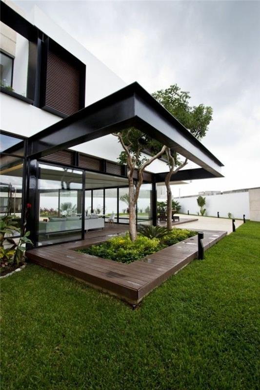 šiuolaikinis minimalistinio stiliaus namas su žalia veja dideliame sode