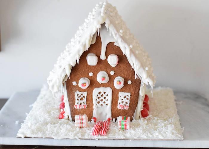 Zencefilli duvarları ve çatısı olan bir kulübede karı taklit etmek için beyaz krema, gurme Noel tatlısı