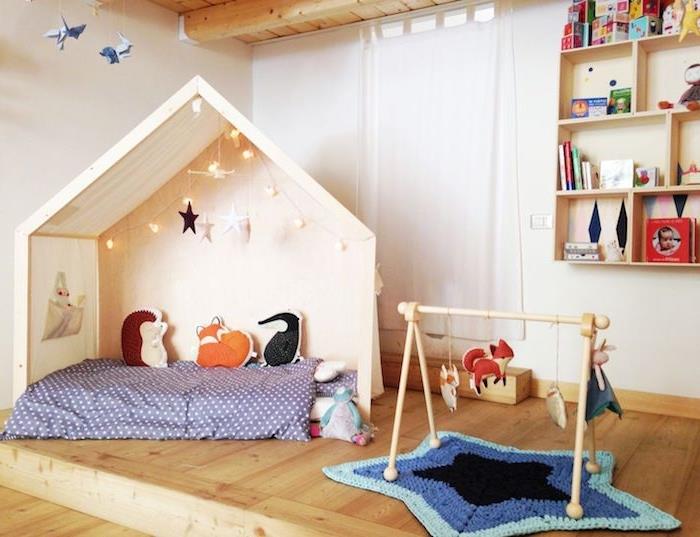 medinė lova su lova su čiužiniu, lengva girlianda ir vaikiškos pagalvėlės vaikams, medinės grindys, žvaigždės formos Montessori žaidimų kilimėlis