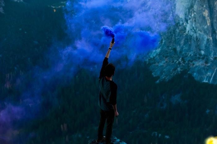 mavi bir bomba tutan adam, bir kayanın tepesinde duran, arka plan tumblr, dağ manzarası
