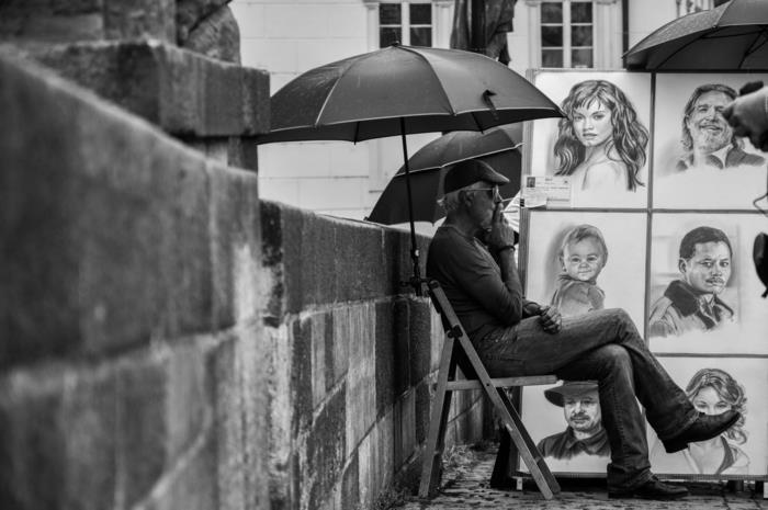 bir sandalyede oturan adam, sigara içiyor, ünlülerin çizimleriyle çevrili, kız çizimi