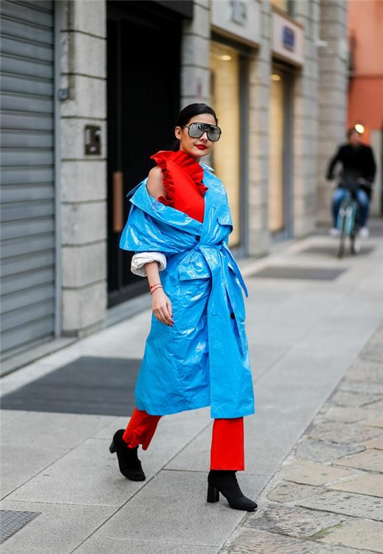 modri nepremočljiv plašč, rdeče hlače, rdeča bluza, prevelika očala, moderna ženska