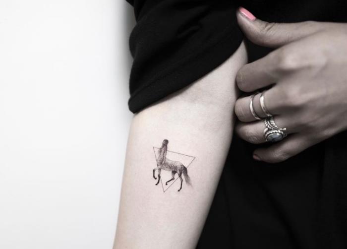 primer izvirne oblikovalske tetovaže z majhno risbo ženskega kentavra, uokvirjenega v minimalističen trikotnik