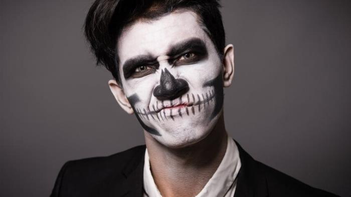 tek renkli cadılar bayramı makyajı, bir adamın yüzünde yüz boyalarıyla oluşturulmuş kafatası