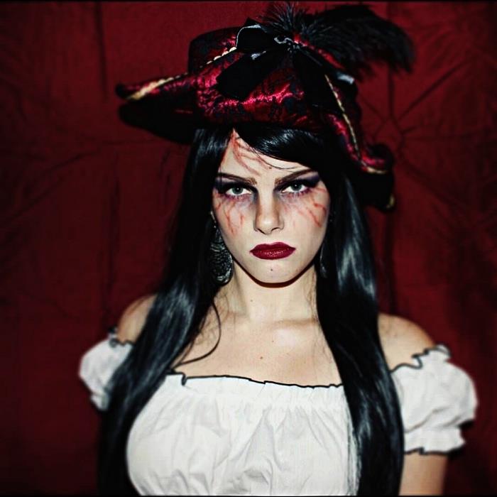 ustvarjalna ženska piratska ličila z narisanimi žilami okoli oči, piratski kostum, ki vključuje domišljijski klobuk in zgornji del ramen