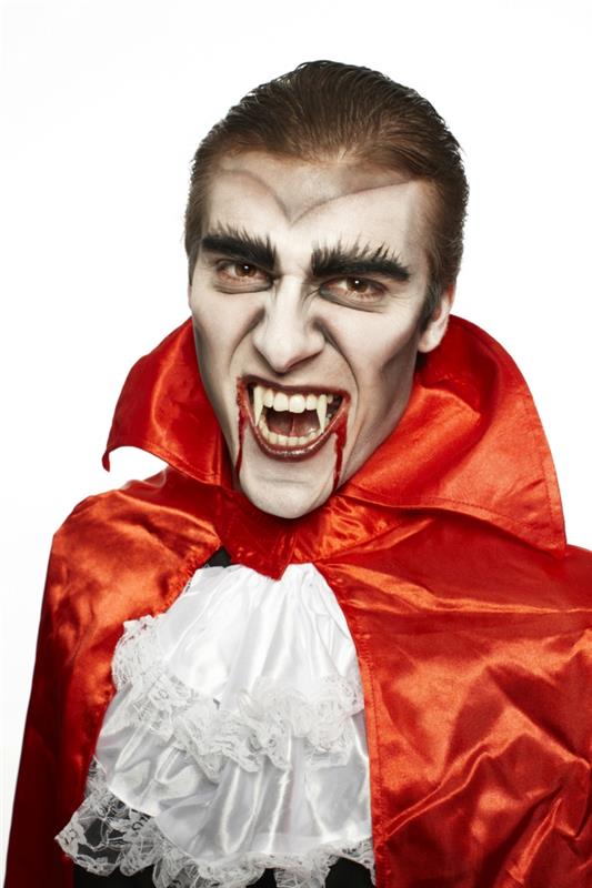vampyras su netikrais vampyro dantimis ir oranžiniu apsiaustu, kruvinos lūpos su netikru krauju