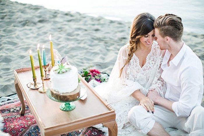 Vestuvės paplūdimyje su labai nedaug svečių, gražus paprastas baltas kreminis pyragas, papuoštas žalia gėlė, šedevro pyrago vaizdas, cukraus pastos figūrėlės menas